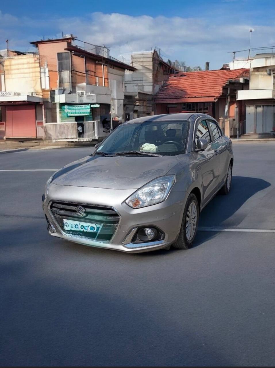 2022 Suzuki Dzire parked on a city street, showcasing its sleek design and factory saddle brown color.