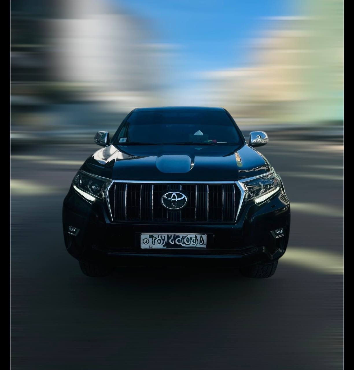 A silver 2019 Toyota Prado rental SUV parked on a clean road, showing the front grille and 18-inch wheels.